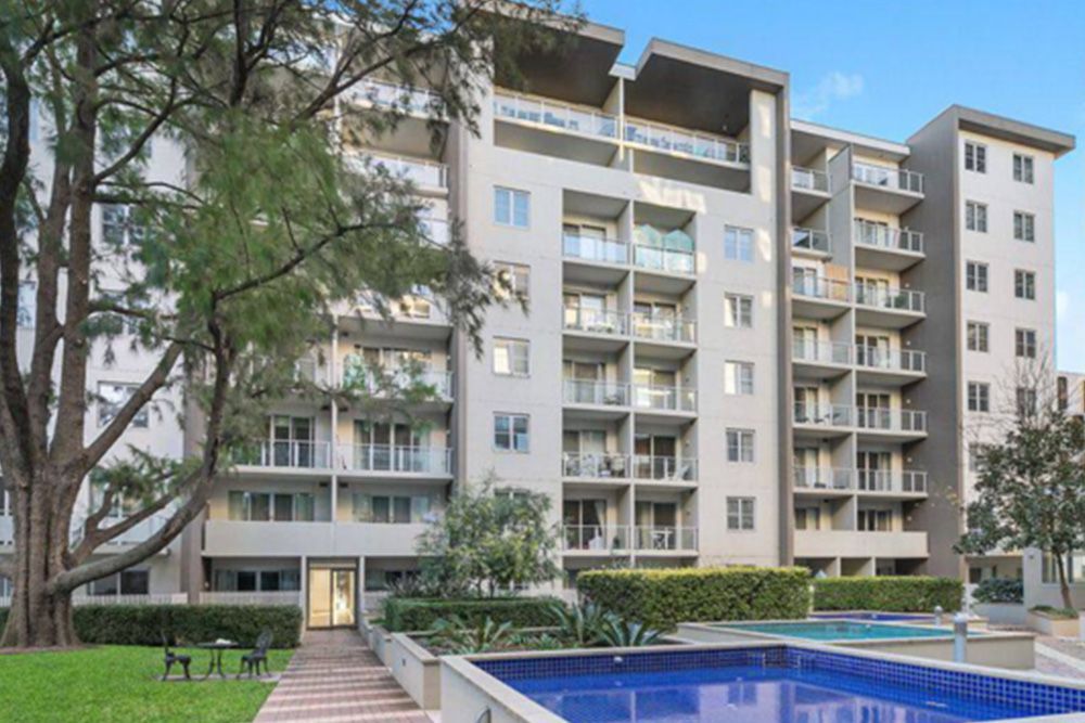 A large apartment building with a swimming pool in front of it