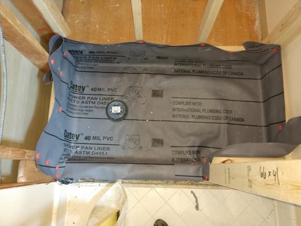 Insulated duct wrapped in gray plastic between wooden framing, with a measuring tape nearby