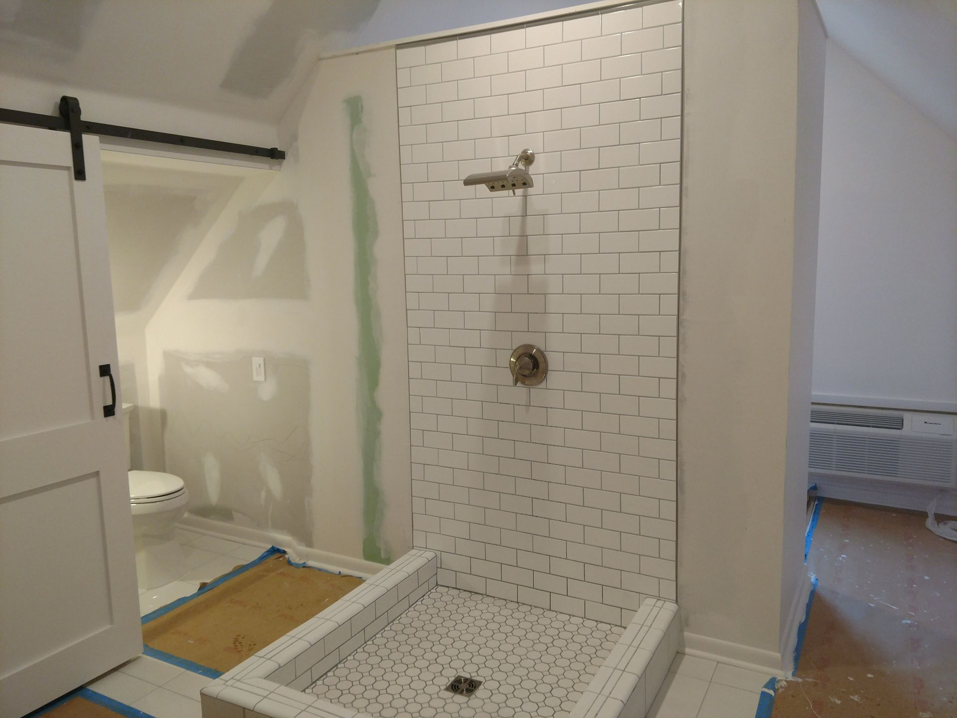Accessible bathroom shower with white subway tile, roll-in shower base, and sliding barn-style door