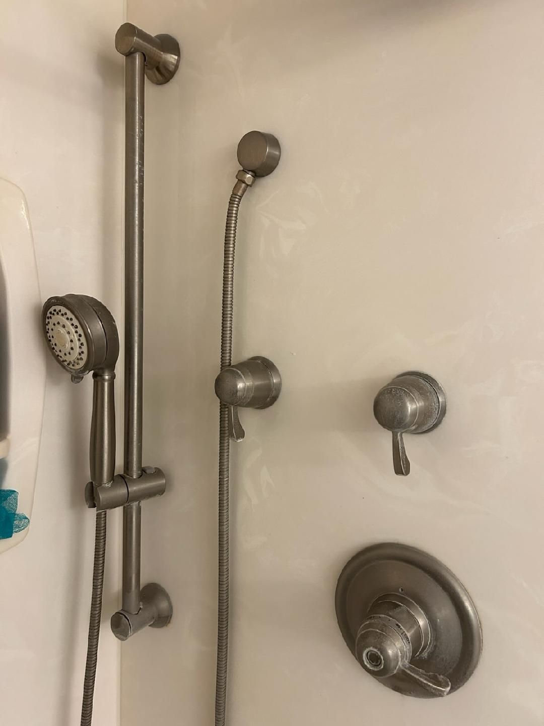 White tiled shower with multiple chrome showerheads, grab bar, and controls.