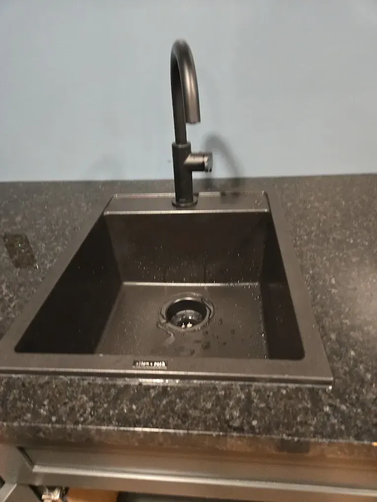 Dark granite kitchen sink with black faucet and empty basin under a countertop