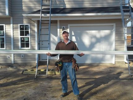 a man standing in front of a house holding a piece of metal