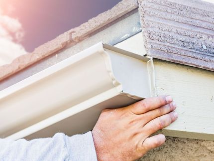 man in white tank top installing a gutter.