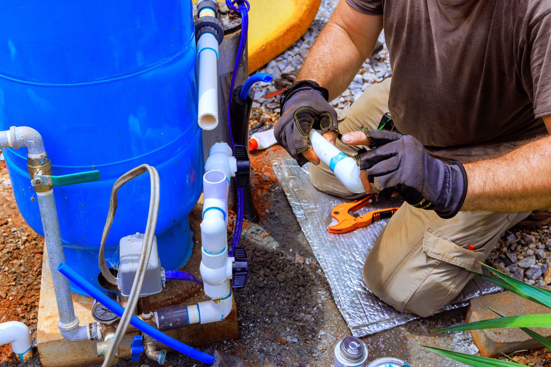 Outdoor well water system with blue tank, filtration, and grey holding tank.