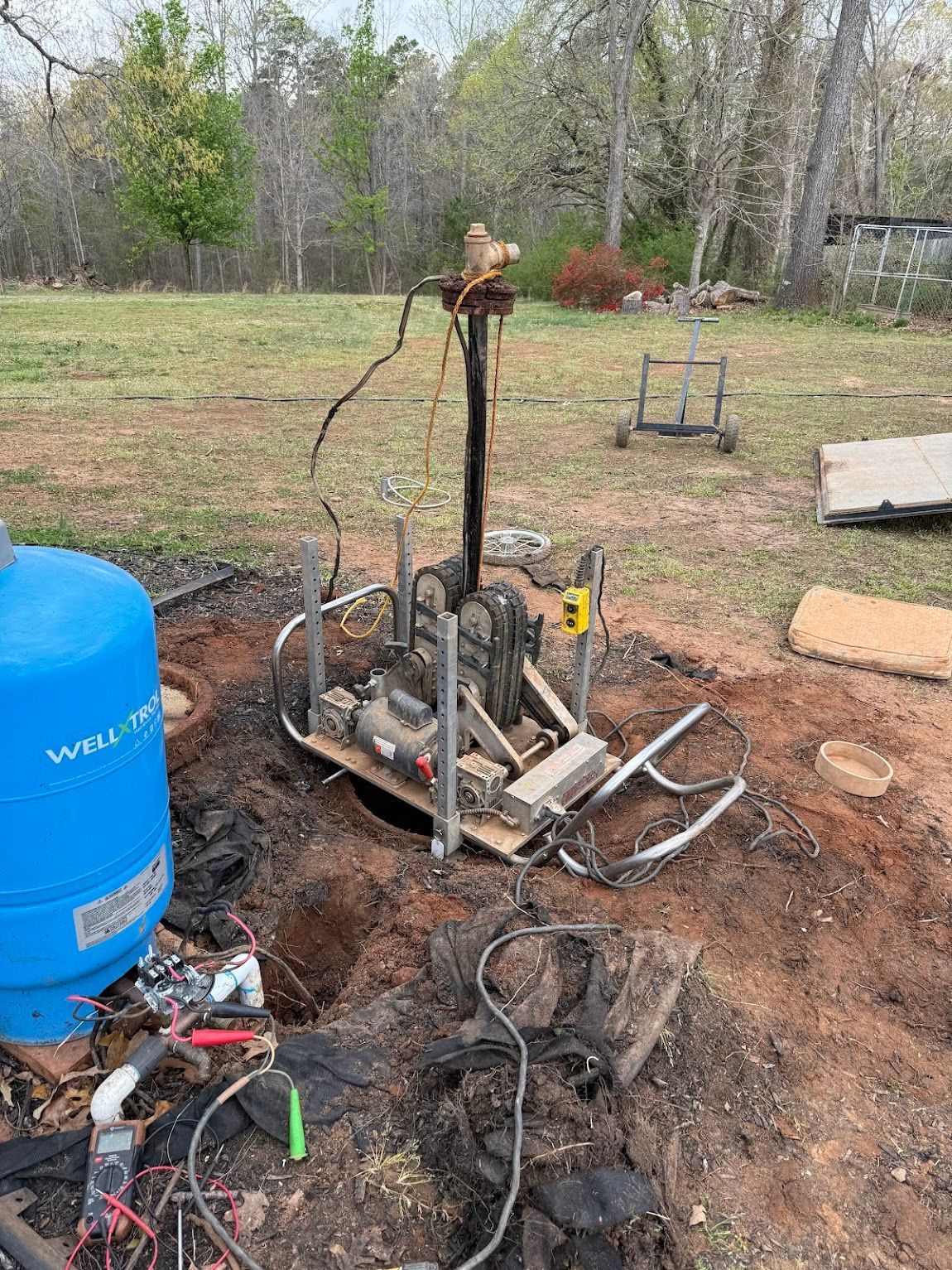 Well pump system with pressure tank and equipment exposed in an outdoor setting.