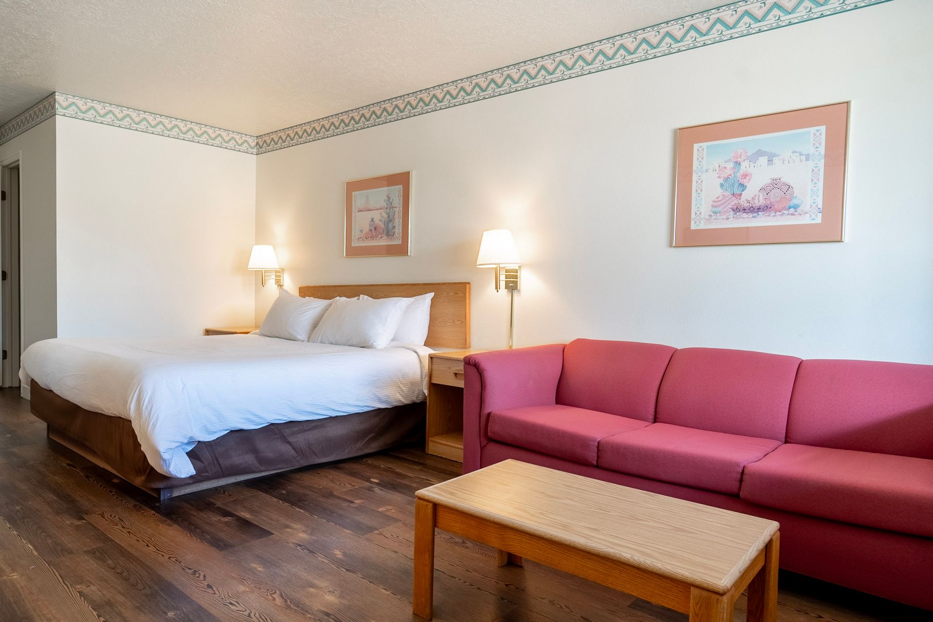 A hotel room with a king size bed and a red couch