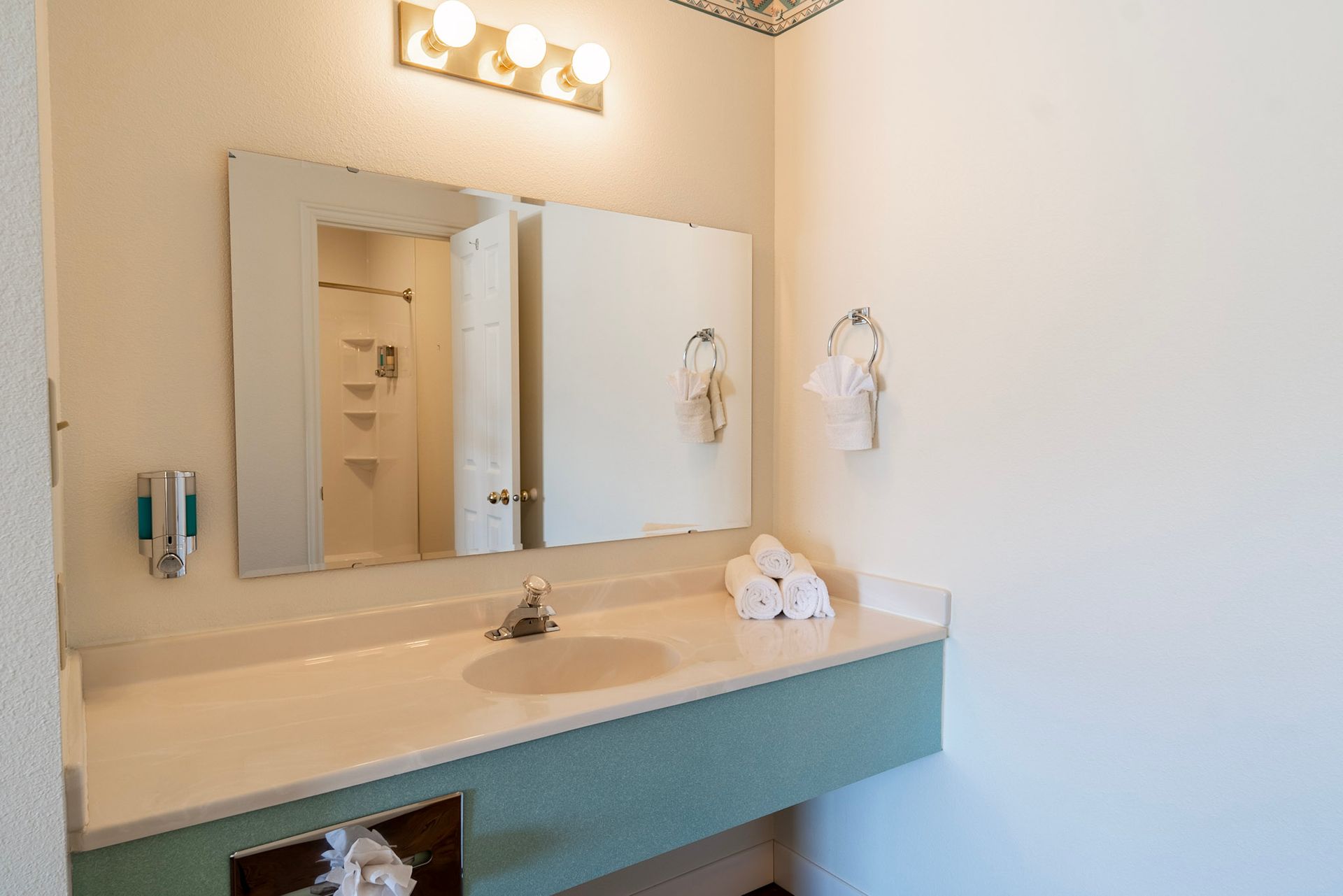 A bathroom with a sink , mirror and towels.