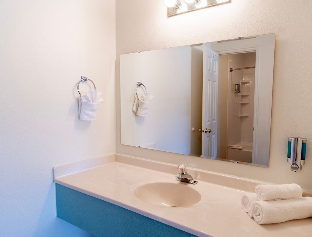 A bathroom with a sink , mirror and towels on the counter.