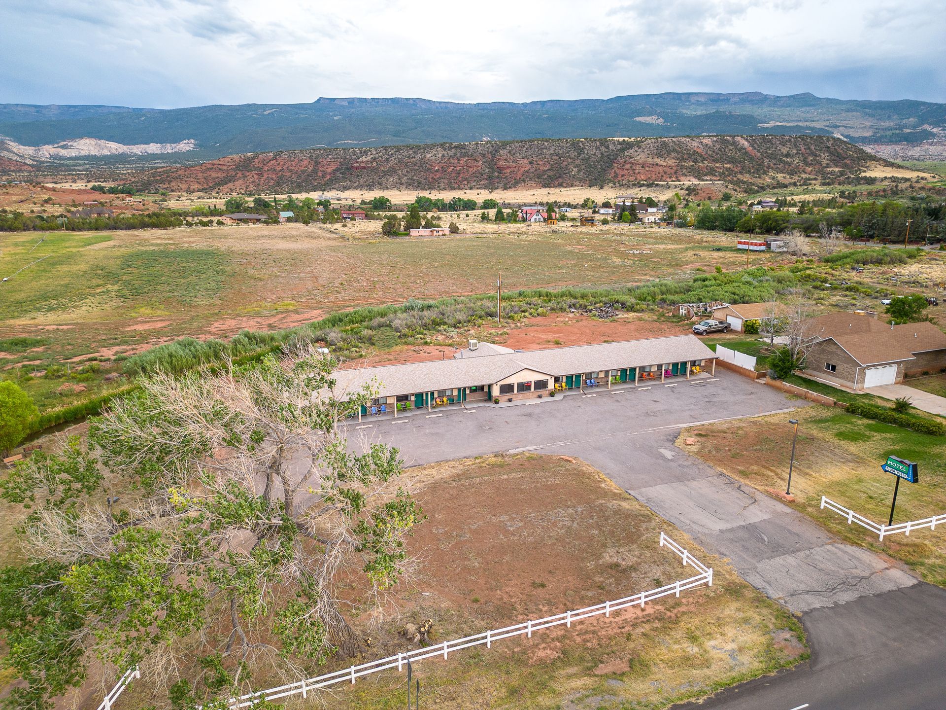 An aerial view of a motel in the middle of a field with mountains in the background.