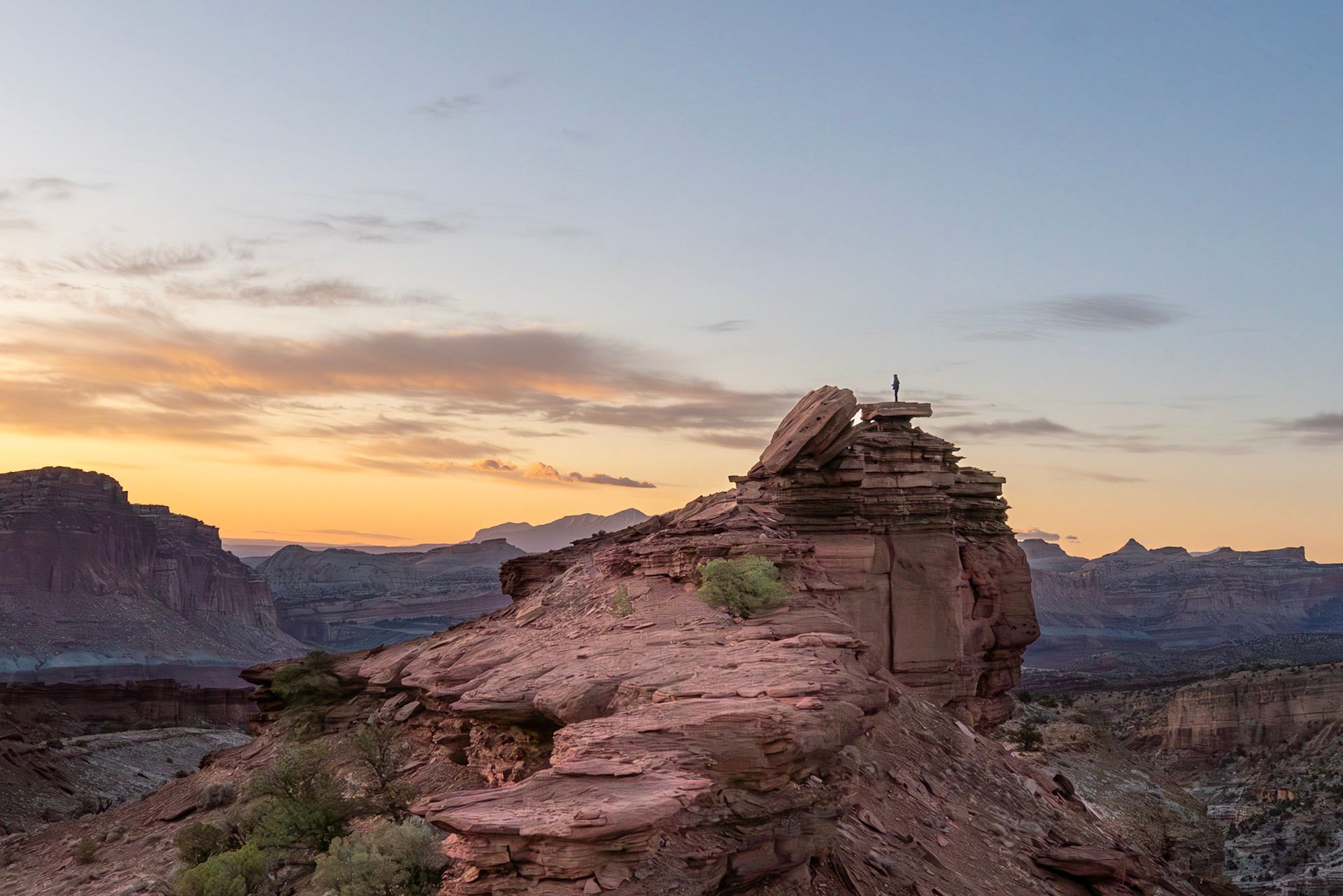 hikers on top or red rocks at sunset