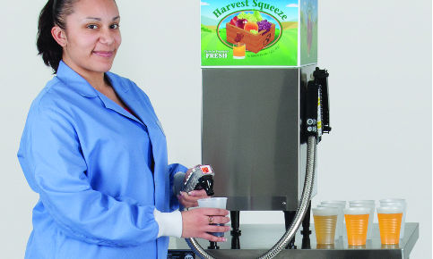 A woman is pouring juice into a cup from a machine.