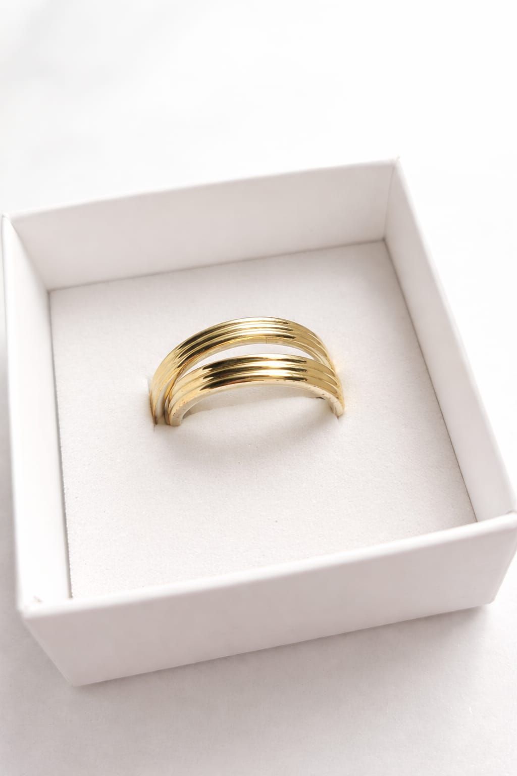 Anillo multibanda de oro en un joyero blanco sobre fondo blanco.