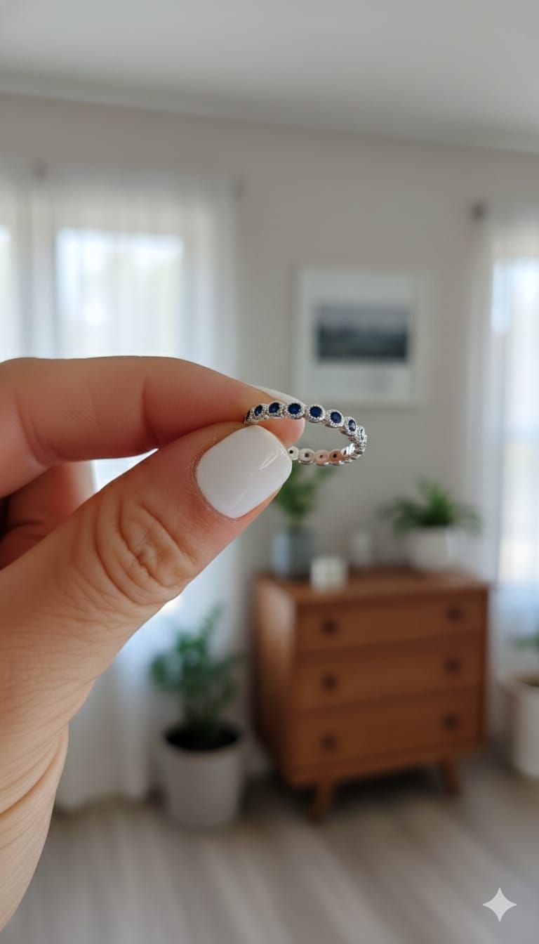 Mano con anillo de plata sostenida contra un jardín desenfocado iluminado por el sol.