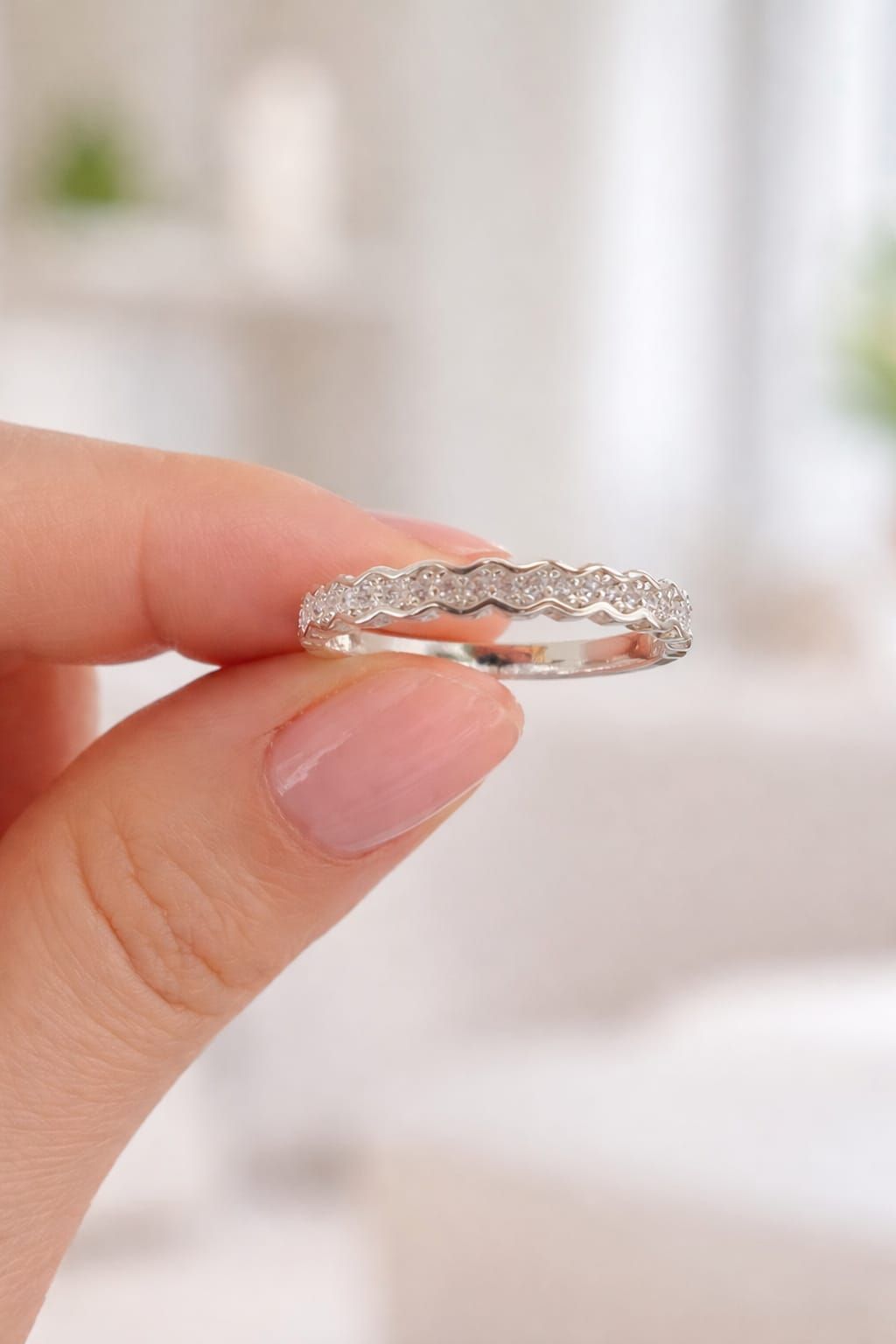 Mano con un anillo de plata adornado con pequeñas piedras transparentes en el dedo anular.