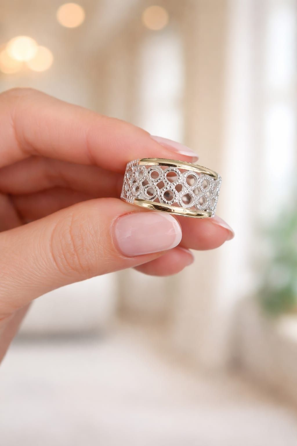 Mano con un anillo de rejilla de plata sobre fondo claro