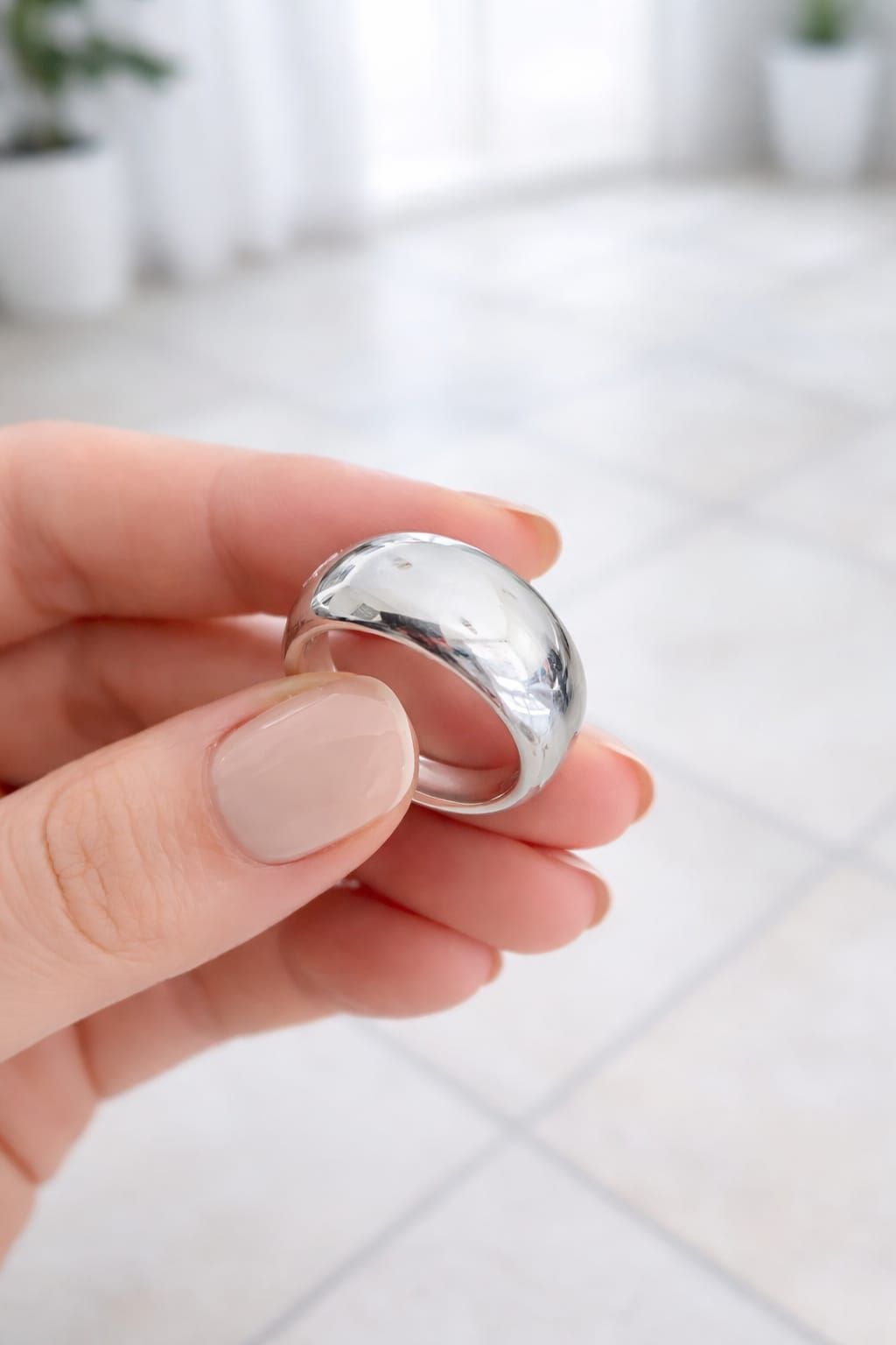 Primer plano de una mano que lleva un anillo de plata brillante en un dedo.