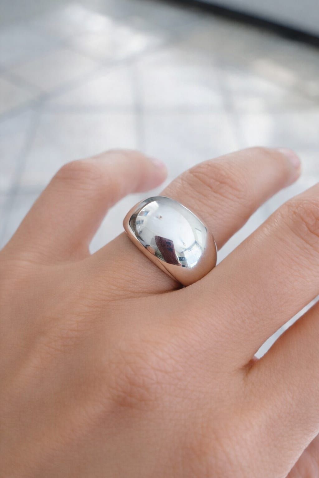 Primer plano de una mano que lleva un anillo de plata brillante en un dedo.