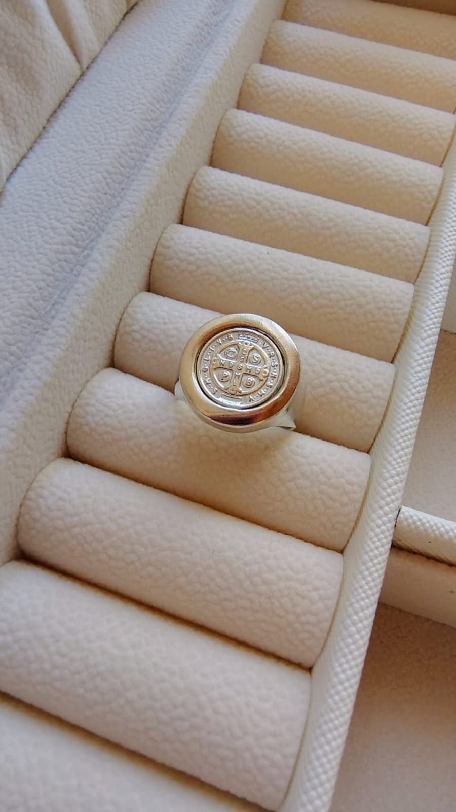 Una mano sosteniendo una pequeña moneda de plata sobre un fondo blanco.
