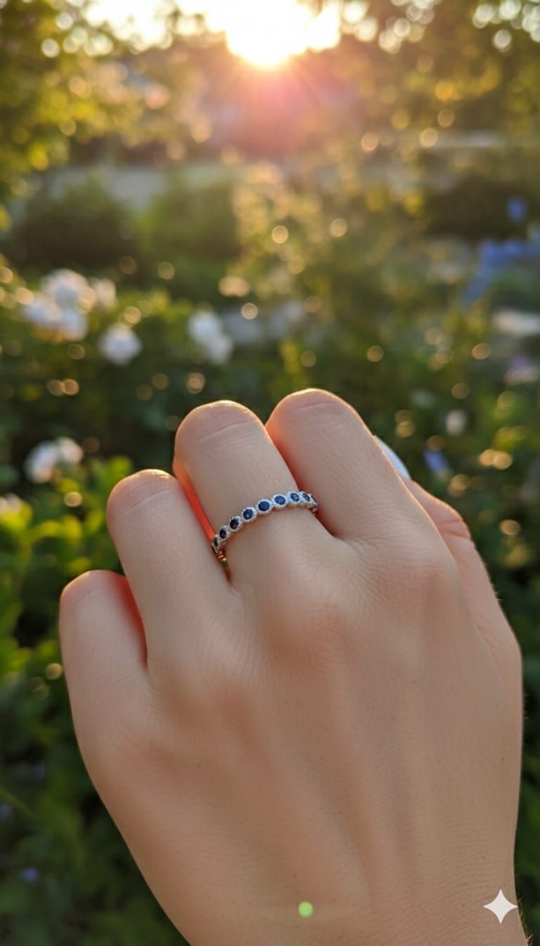 Mano con anillo de plata sostenida contra un jardín desenfocado iluminado por el sol.
