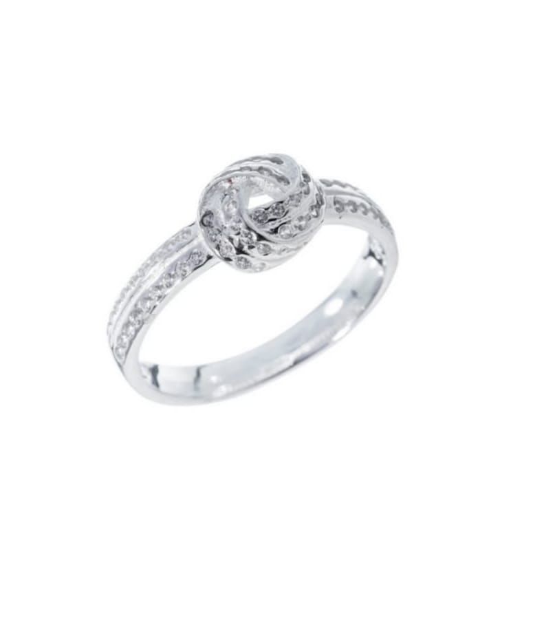 Primer plano de un anillo de plata con diamantes en un dedo, con una piedra central redonda.