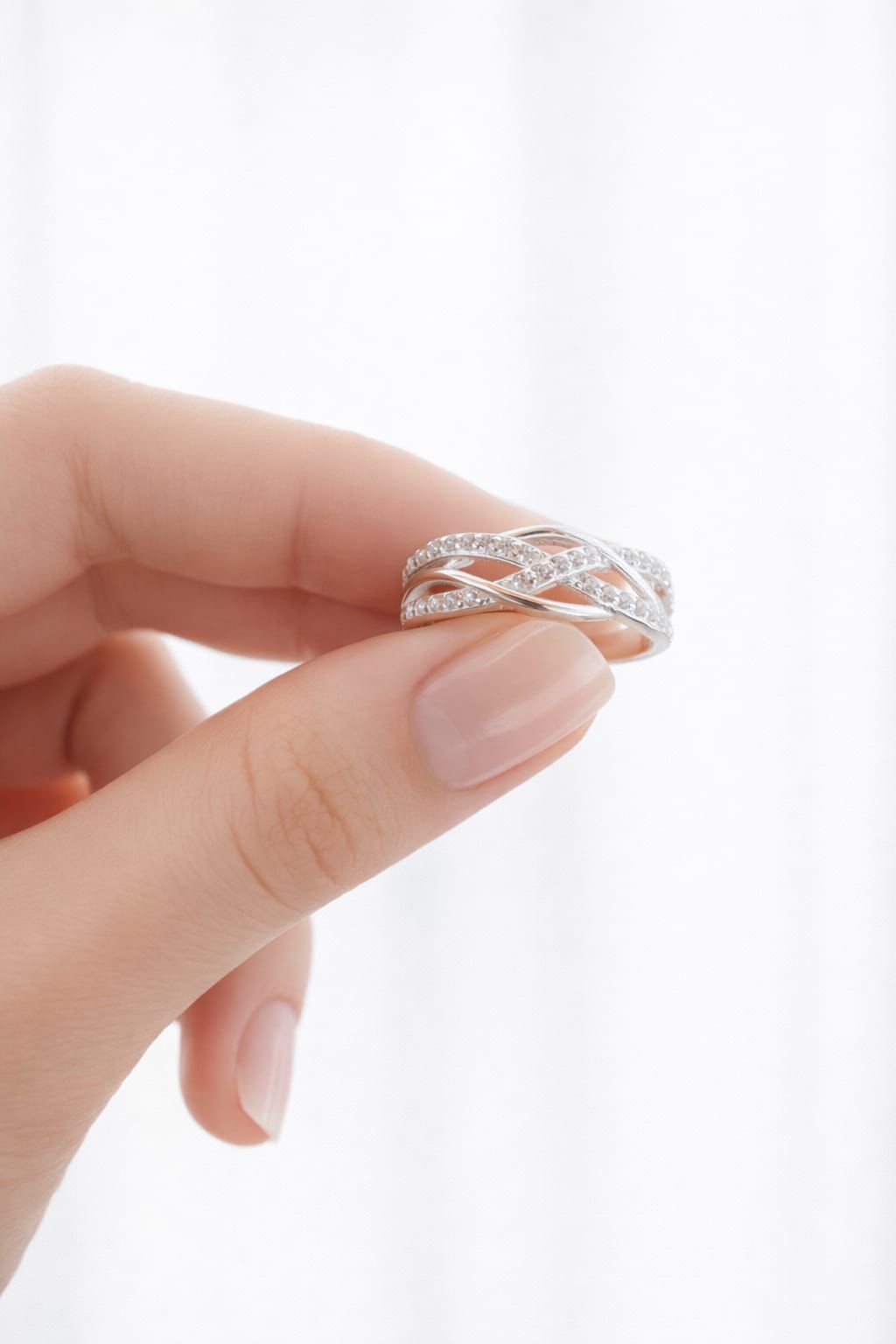 Anillo de plata en un joyero blanco sobre una superficie con iluminación tenue y luces difuminadas al fondo.