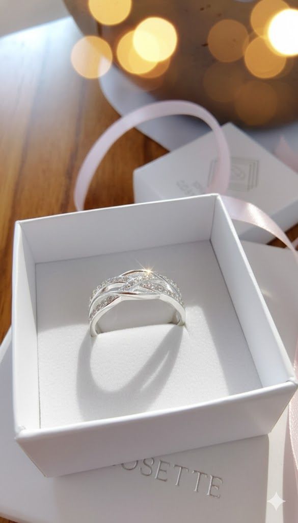 Anillo de plata en un joyero blanco sobre una superficie con iluminación tenue y luces difuminadas al fondo.