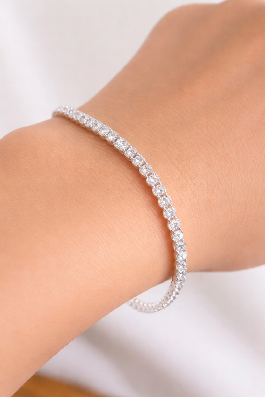 Pulsera de plata con diamantes de imitación en una muñeca sobre un fondo claro.