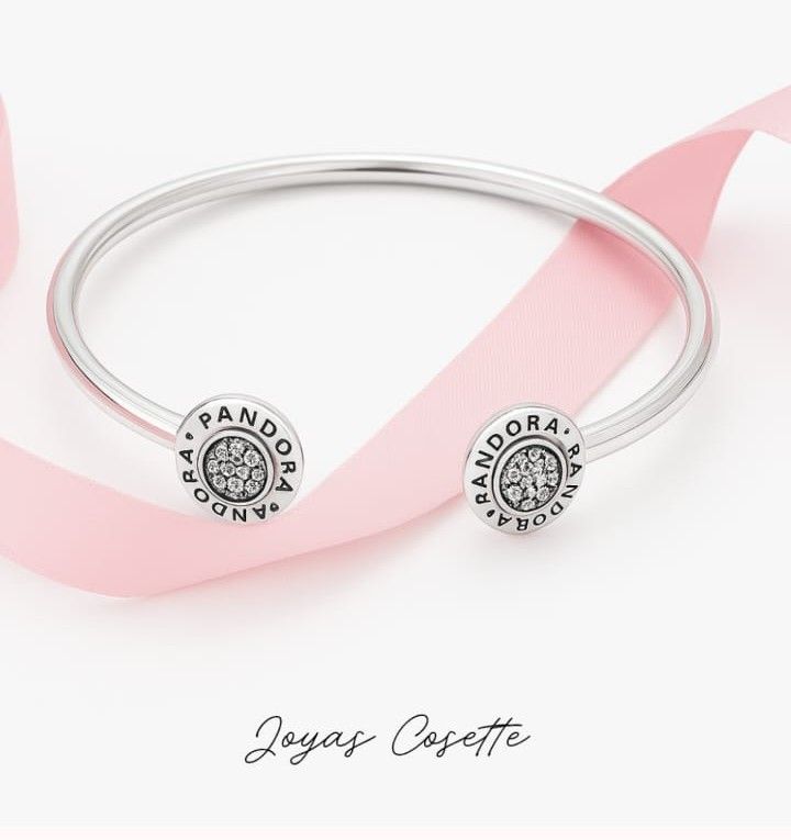 Dos pulseras Pandora de plata con dijes en una muñeca de piel clara, mostradas sobre un fondo blanco.