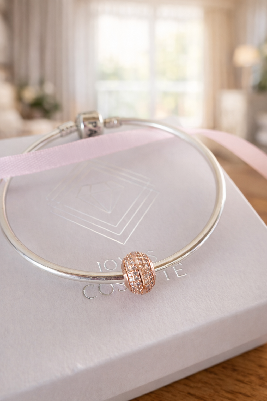 Collar de oro rosa sobre una caja de regalo blanca con una cinta rosa pálido en una habitación con iluminación tenue.