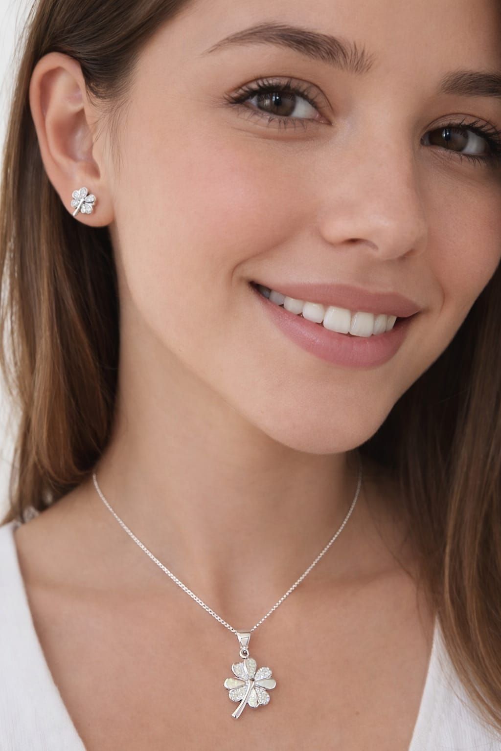 Retrato de cerca de una mujer sonriente que lleva un collar de flores de plata y pendientes a juego.