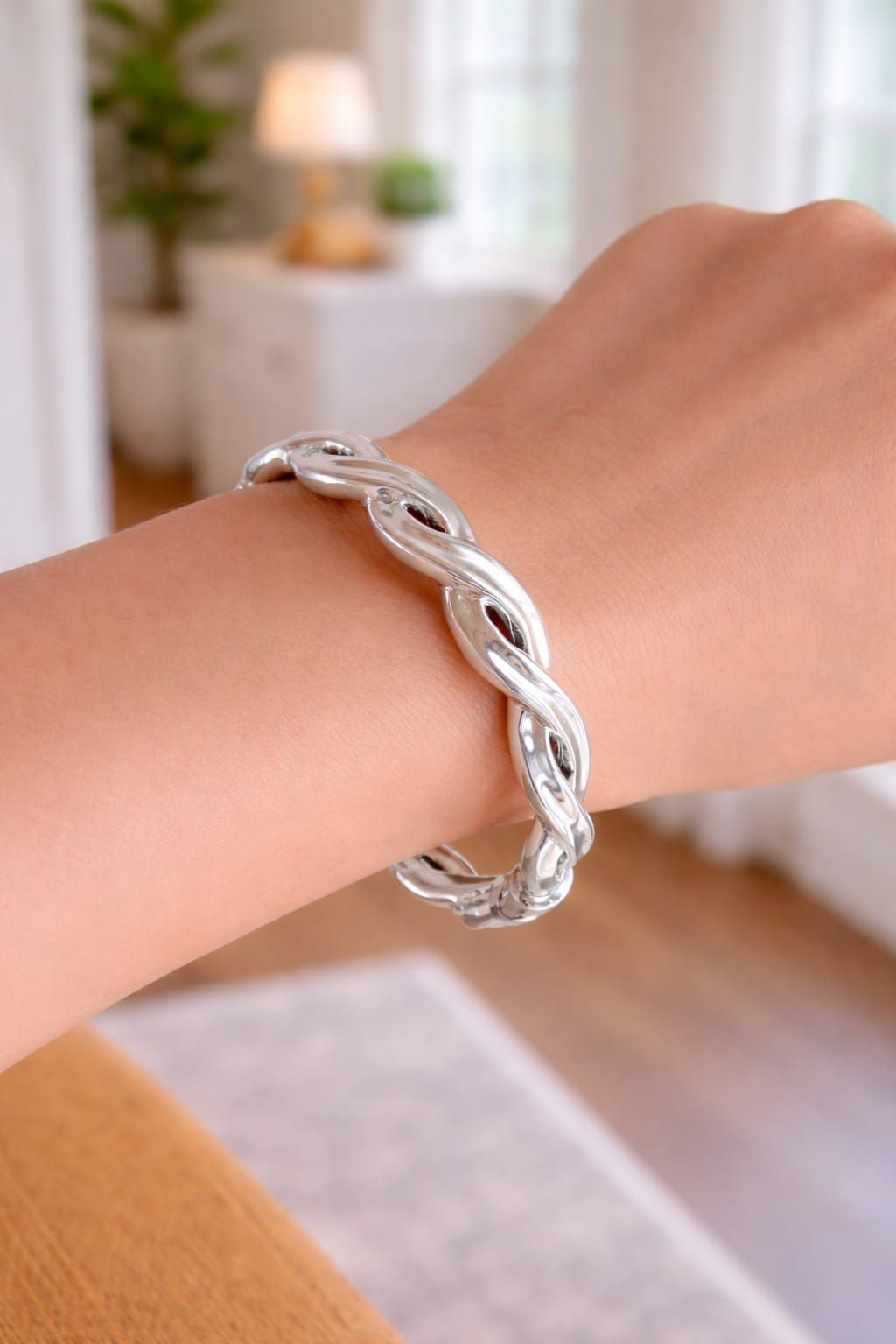 Pulsera de cadena de plata en una muñeca en un ambiente interior con iluminación tenue.