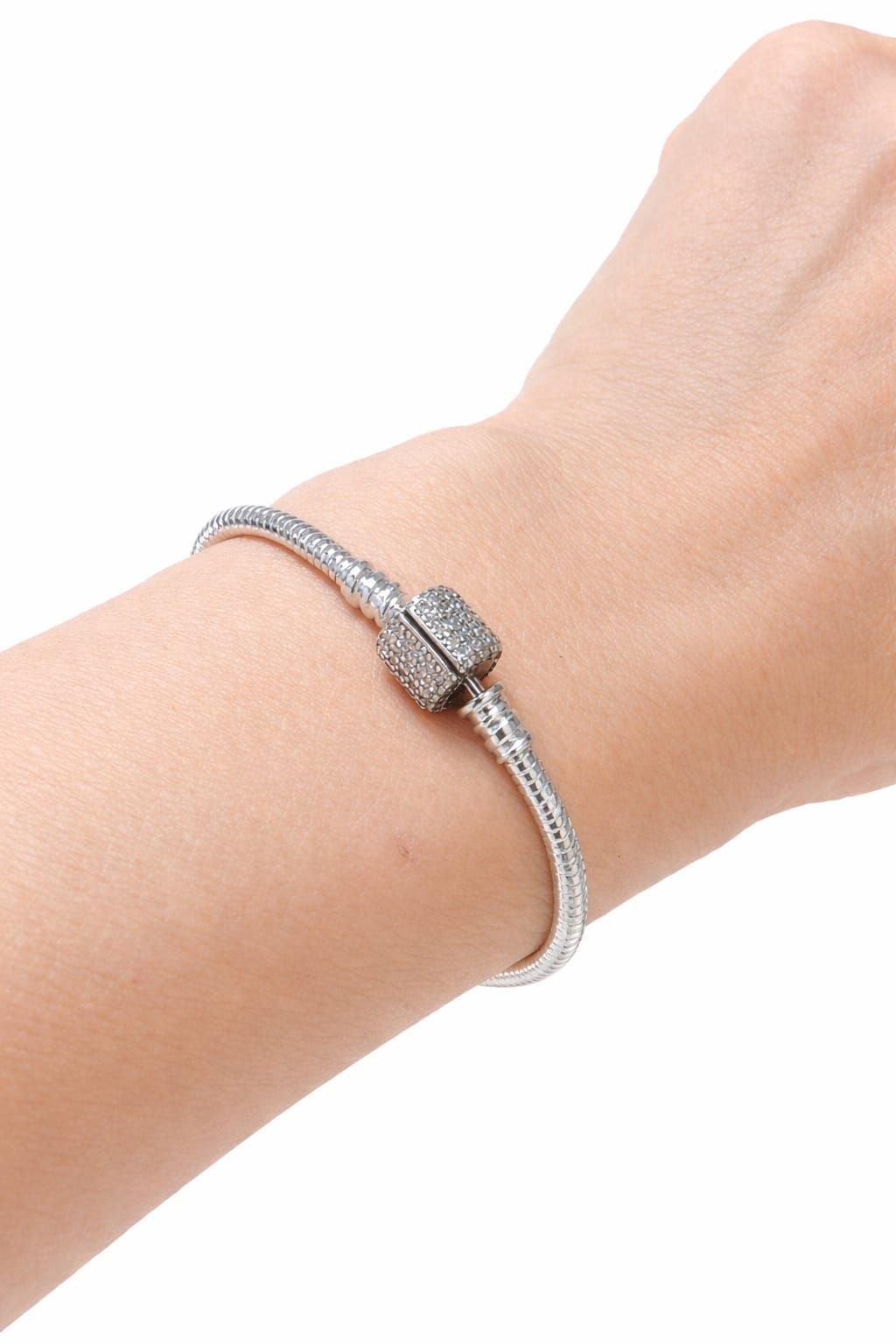 Primer plano de una muñeca con una pulsera de cuentas plateadas con un cierre decorativo.