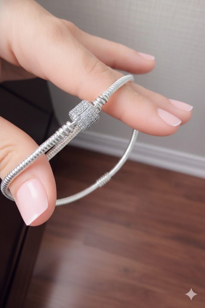 Primer plano de una muñeca con una pulsera de cuentas plateadas con un cierre decorativo.