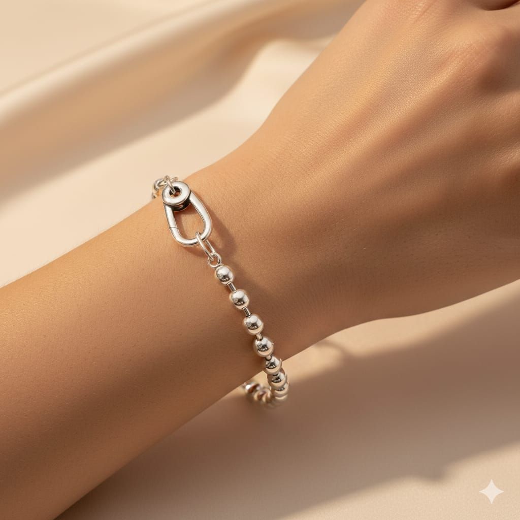 Pulsera de cuentas plateadas en una muñeca sobre un fondo beige suave.