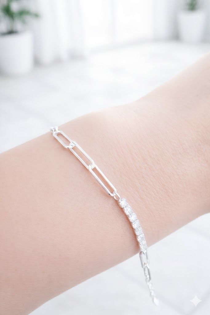 Pulsera de cadena plateada en una muñeca sobre un fondo blanco brillante.