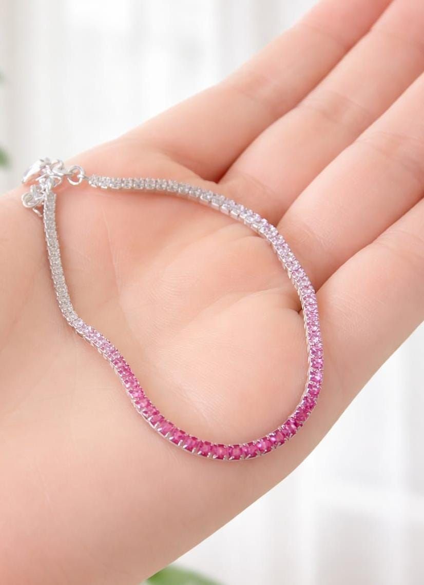 Mano que lleva una pulsera de cuentas rosas y plateadas con un colgante de cadena.