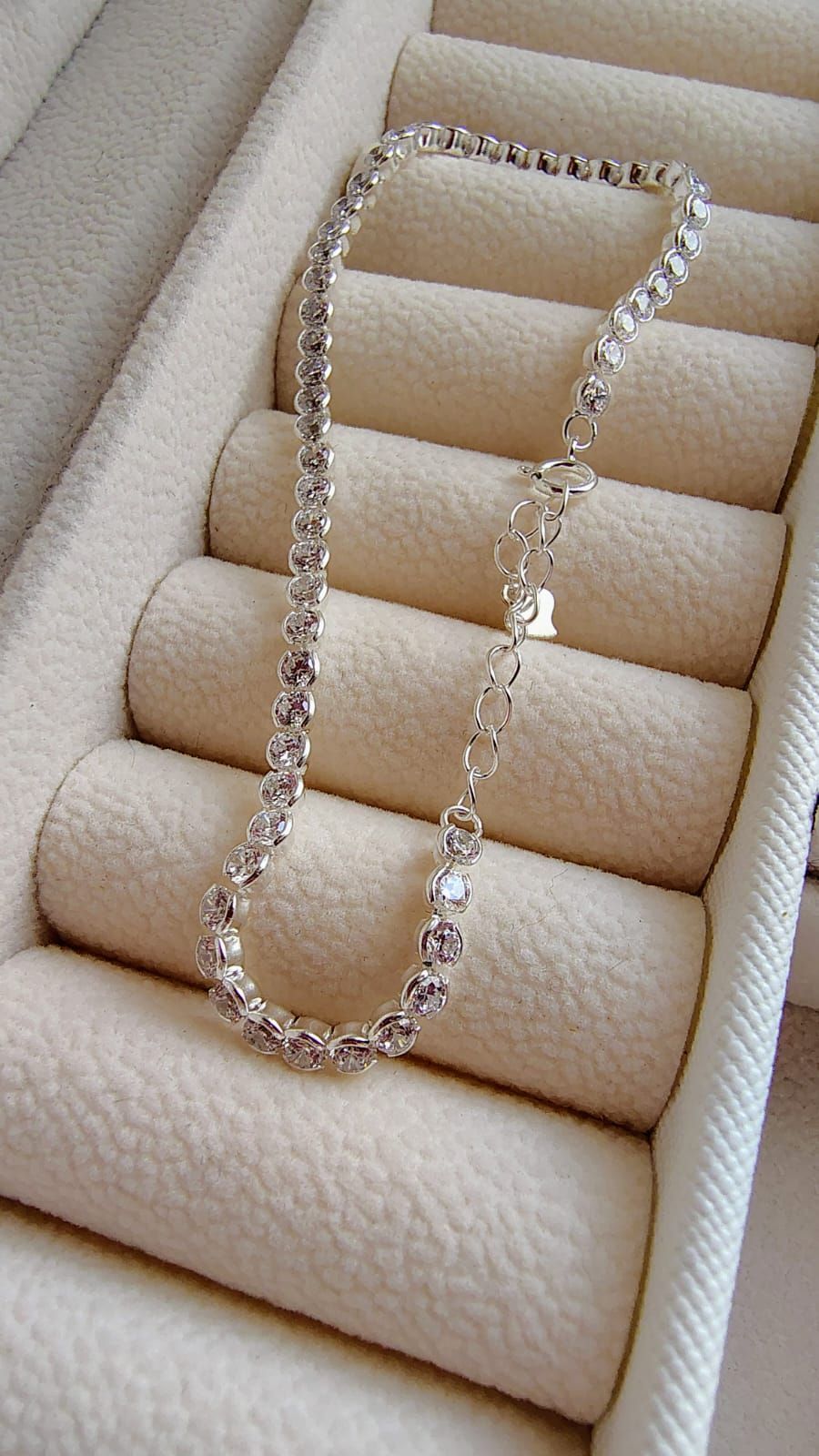 Pulsera de plata con diamantes de imitación en una muñeca sobre un fondo claro.