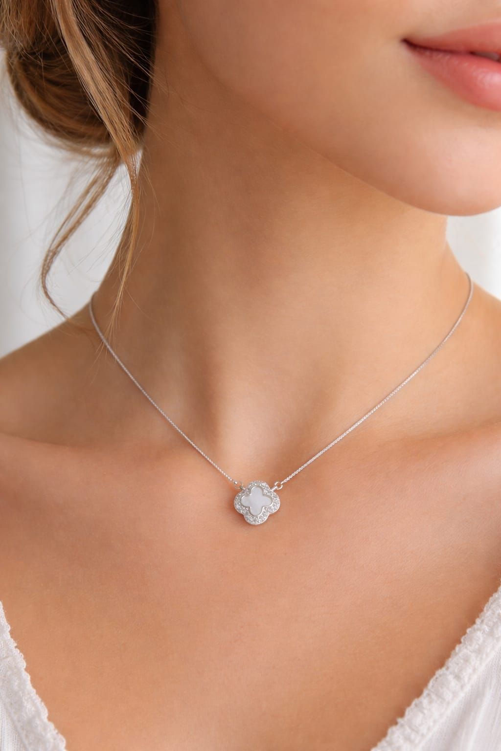 Primer plano de una mujer que lleva un delicado collar de plata con un pequeño colgante.