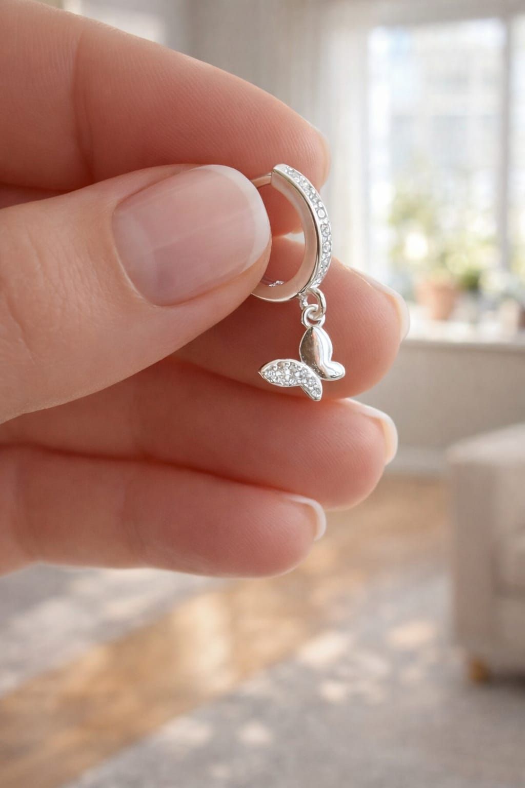 Mano sosteniendo un pequeño pendiente colgante de plata con un dije de hoja y pequeños detalles de cuentas.