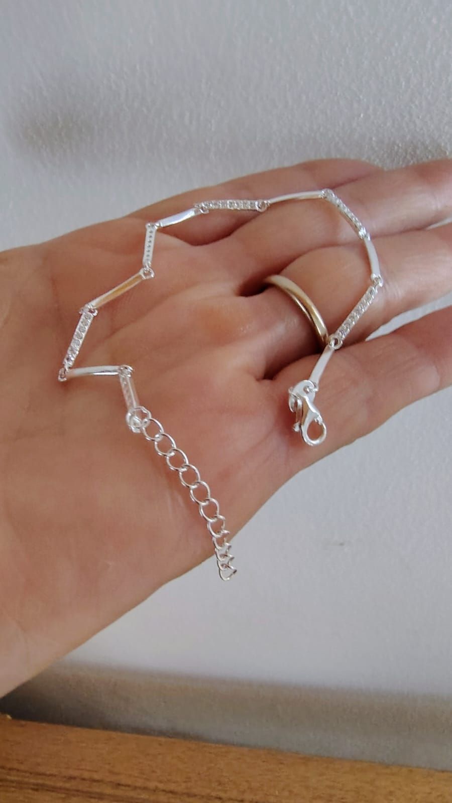 Pulsera de cuentas de plata en una muñeca sobre una mesa de madera.