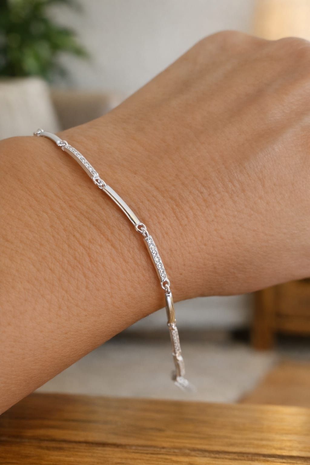 Pulsera de cuentas de plata en una muñeca sobre una mesa de madera.