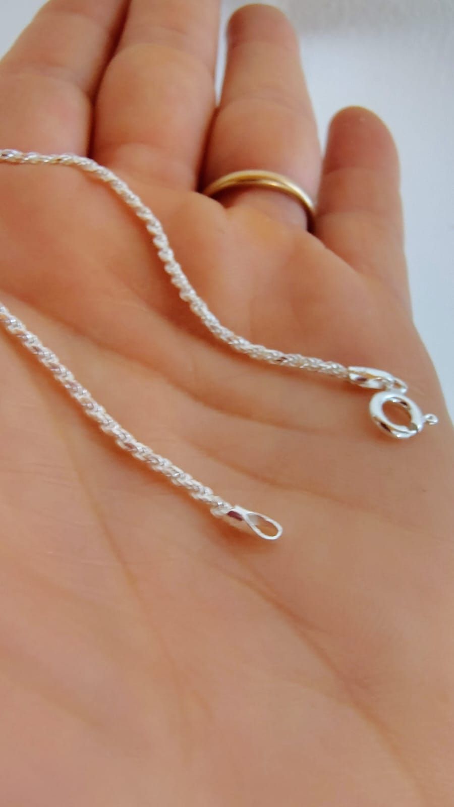Pulsera de cadena plateada en una muñeca sobre un fondo suave y desenfocado.
