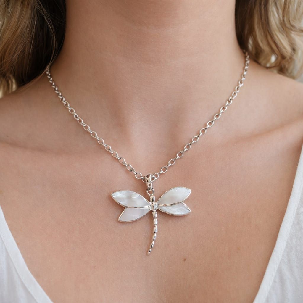 Collar con colgante de libélula plateada en el cuello de una persona, con alas de piedras preciosas blancas y transparentes.