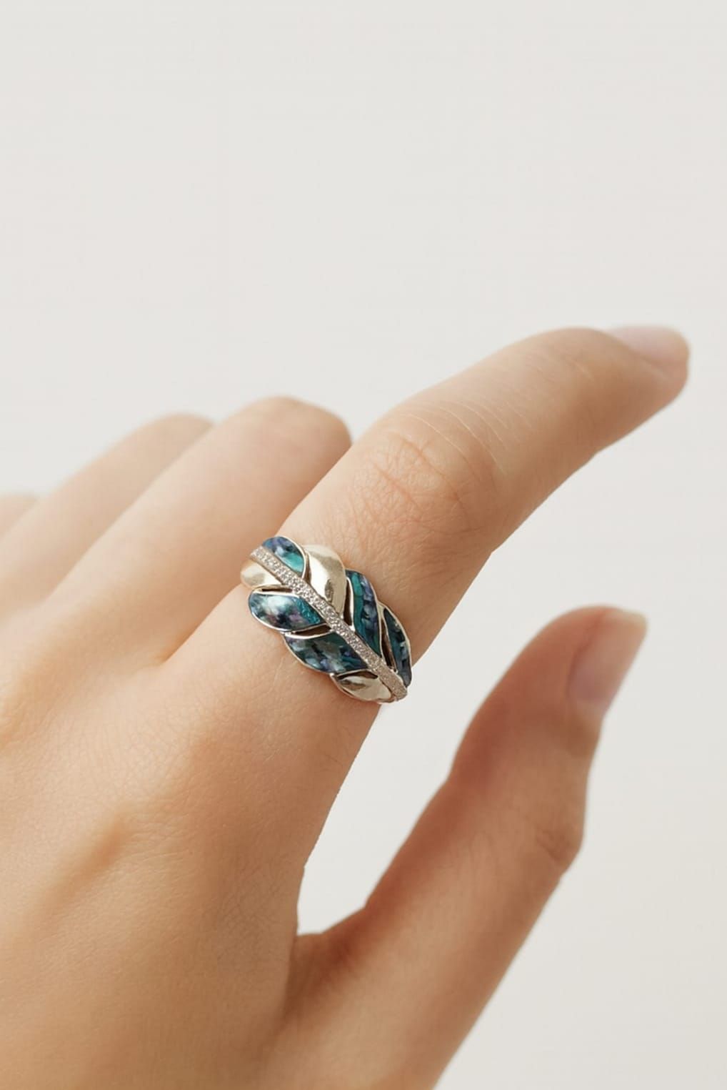Mano con un anillo de piedra preciosa azul sobre fondo claro