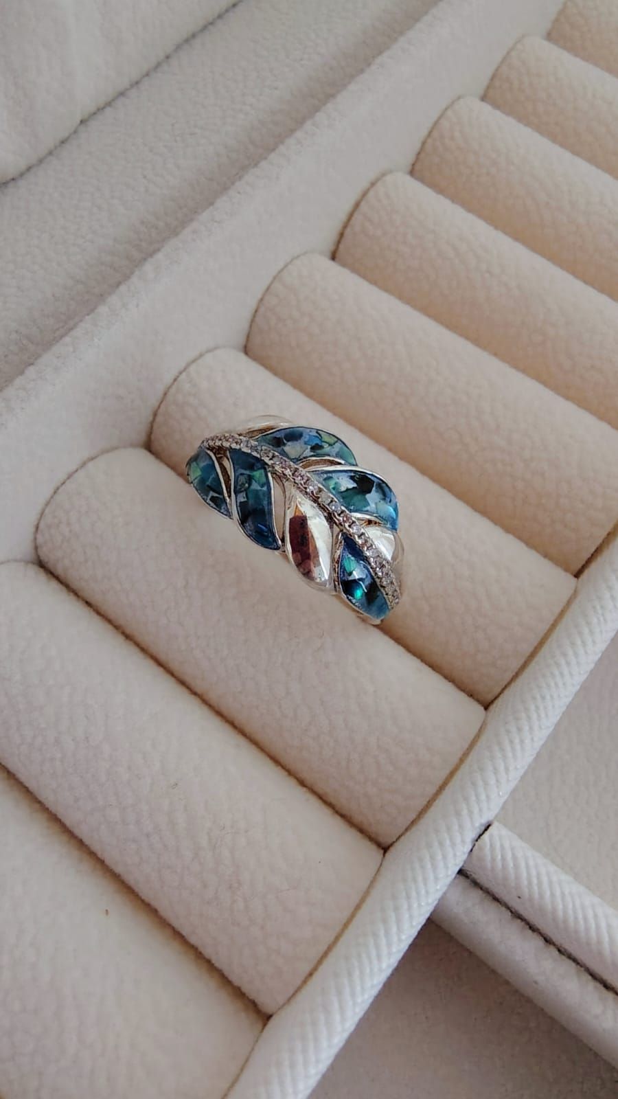 Mano con un anillo de piedra preciosa azul sobre fondo claro