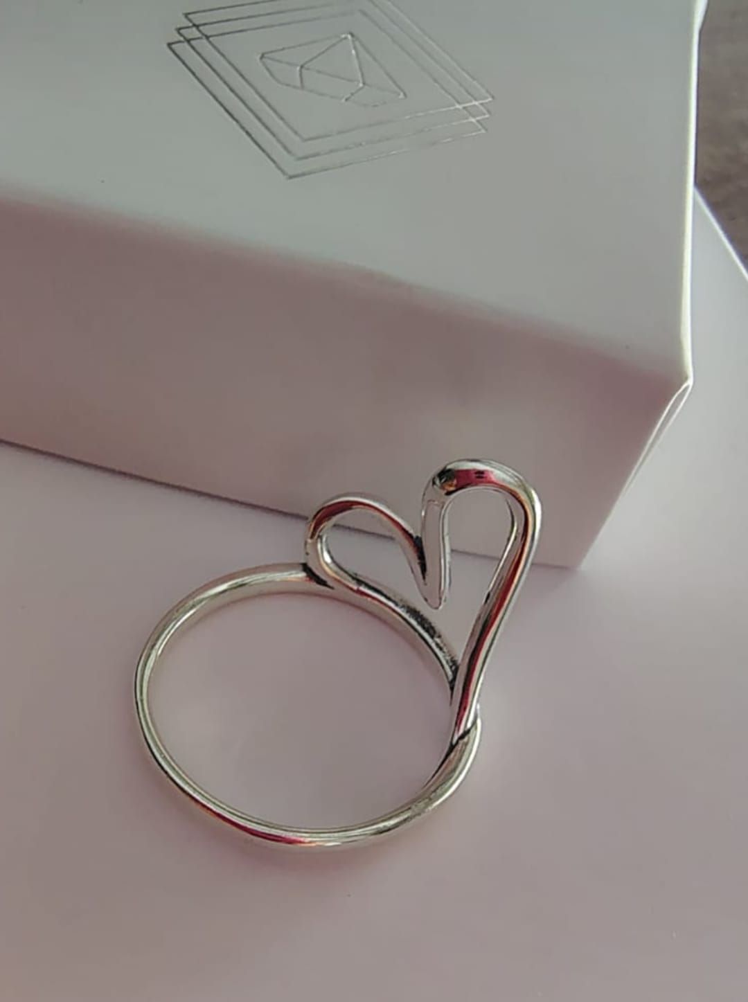 Mano con un anillo de mariposa de plata sobre fondo blanco