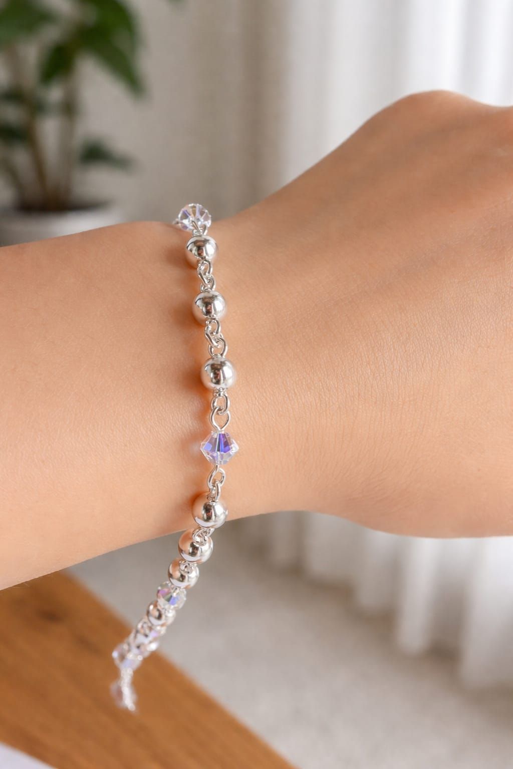 Pulsera de cristal en una muñeca, con piedras transparentes y moradas en una habitación luminosa.