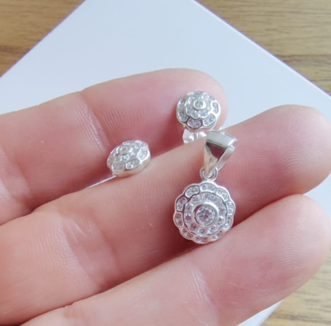 Pendientes de plata en una caja blanca de JOYAS ROSETTE con un logotipo geométrico sobre fondo azul marino.