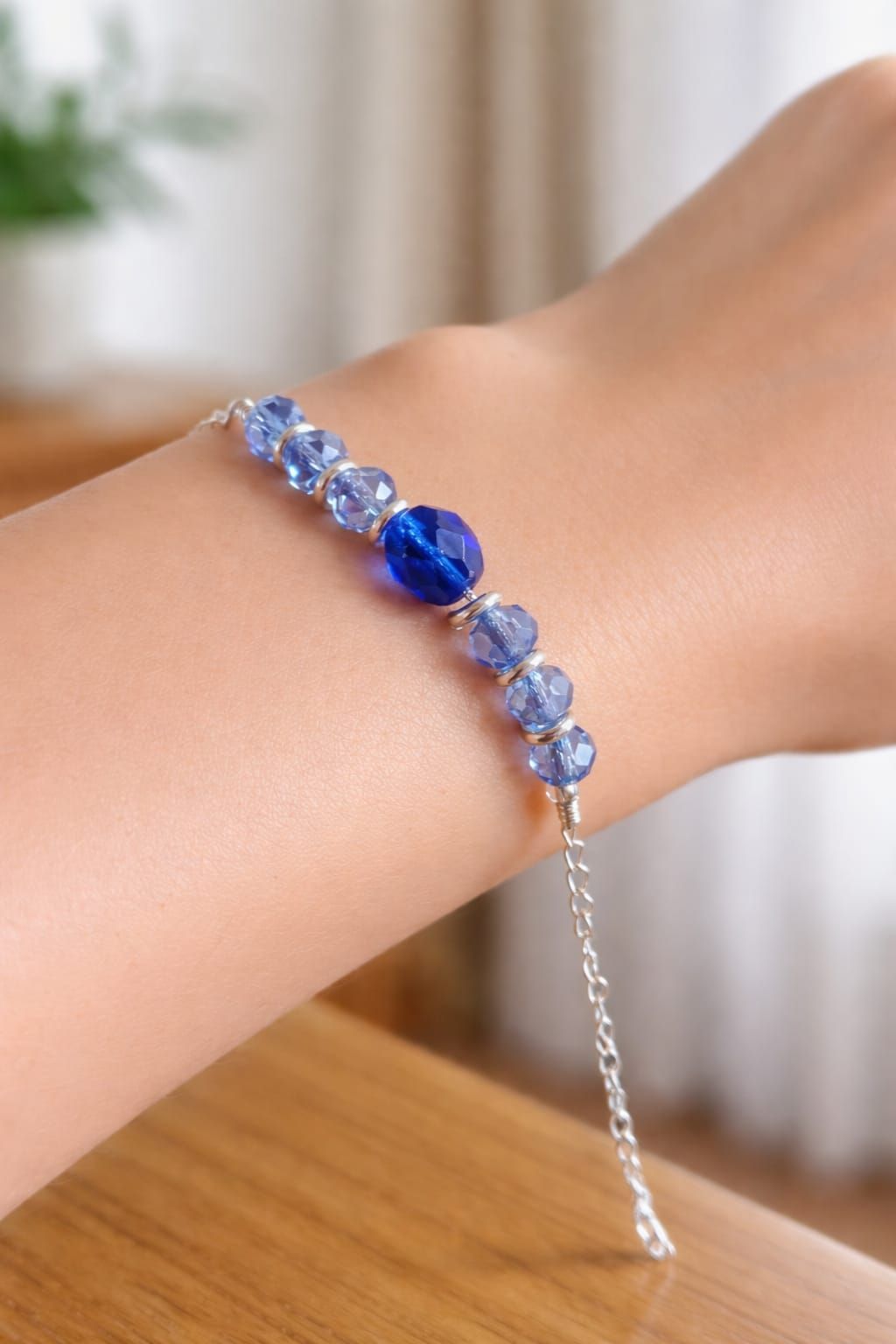 Pulsera de cuentas azules con cadena plateada que se lleva en la muñeca.
