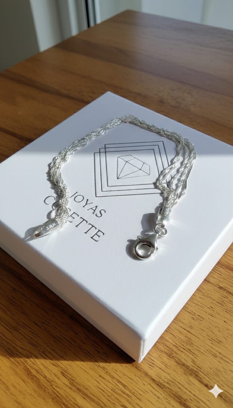 Una mano con tres delicadas pulseras de cadena de plata sobre un fondo claro.